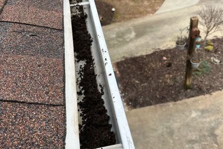 Technician clearing sand like granules from a gutter in simpsonville sc